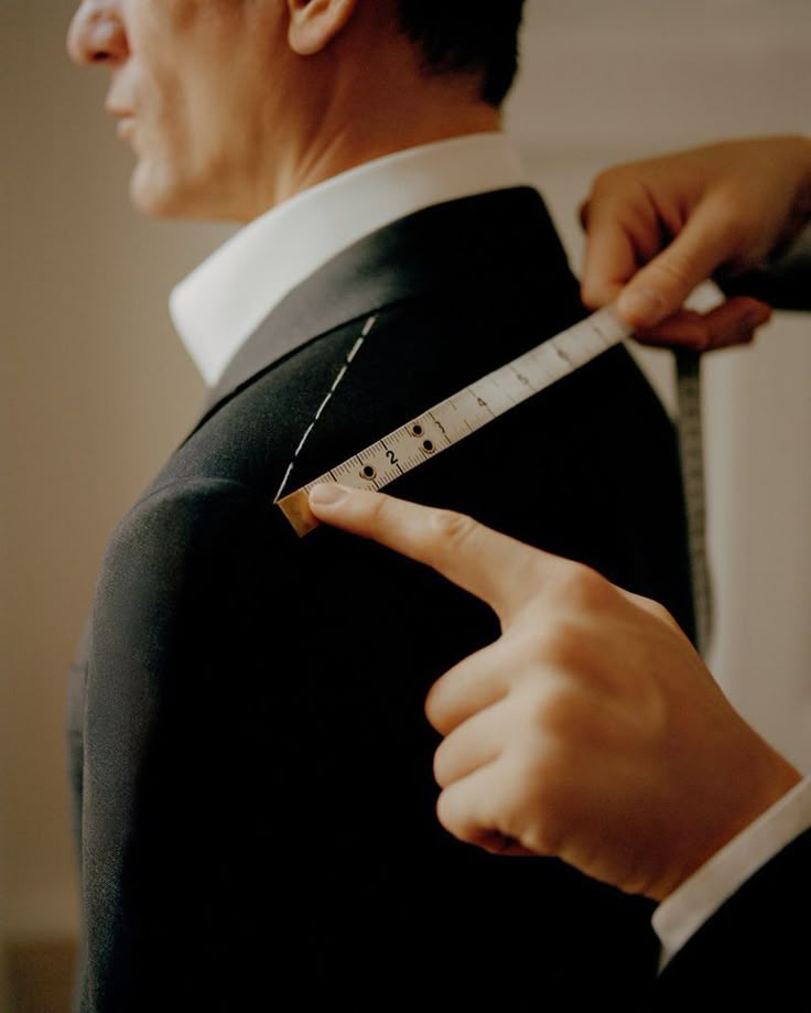 Un croitor INSIGNUM ia măsurători precise pentru umărul unui sacou, pas esențial în procesul de creare a unui costum made-to-measure.