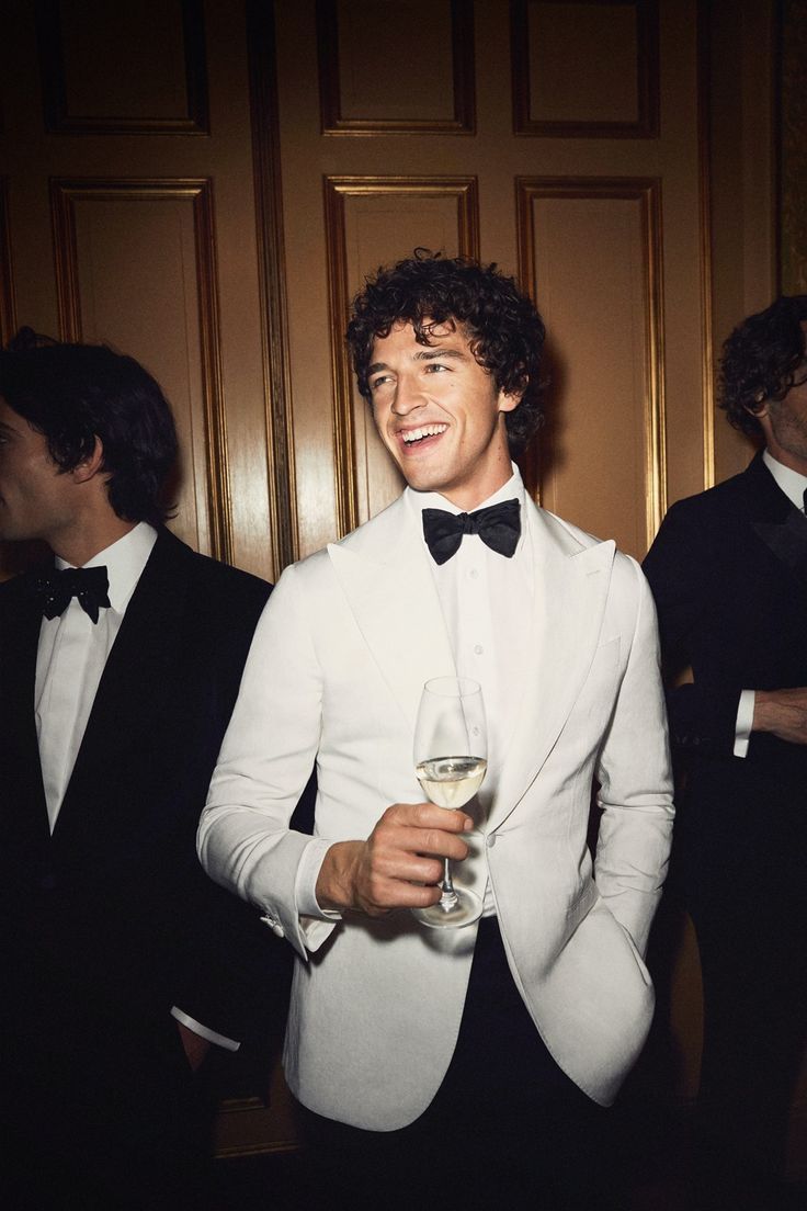 Bărbat elegant într-un tuxedo alb made-to-measure cu papion, la un eveniment special de seară, creat de INSIGNUM.